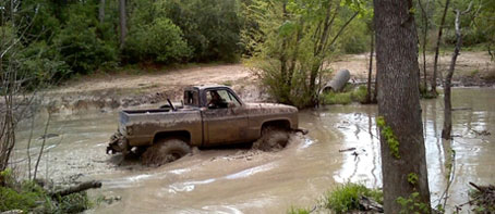 A truck powering through muddy water at Creekside Offroad Ranch